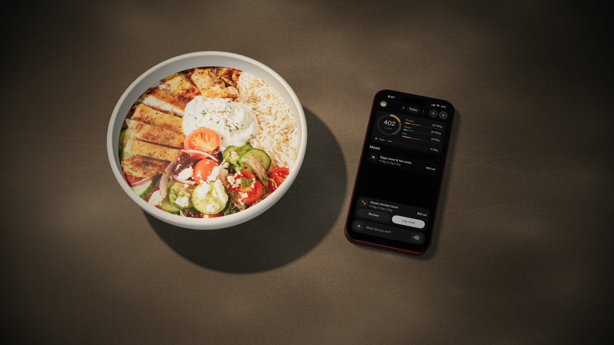 An iPhone showing Ore beside a Greek chicken bowl on a stone counter